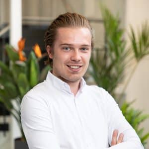 Portret van lachende man in wit overhemd met armen over elkaar voor kantoorplanten