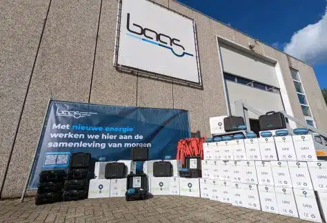 Stacked white boxes marked UNI and black equipment cases in front of a building with a large banner