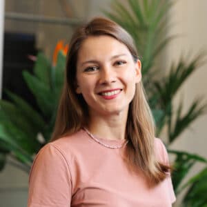 Portret van een lachende vrouw met lang haar in roze T-shirt voor planten met oranje bloemen