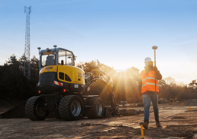 Topógrafo con un UNI-GR2 junto a una excavadora con control de maquinaria GPS 3D UNI-Machine