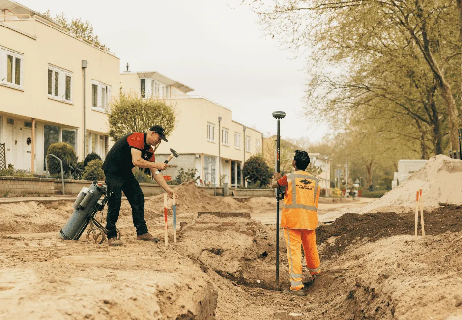 Two workers setting out points with a UNI-GR2 GNSS receiver on a residential street