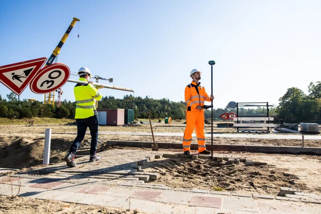 Two site workers surveying in public space with a UNI-GR2 on a survey pole