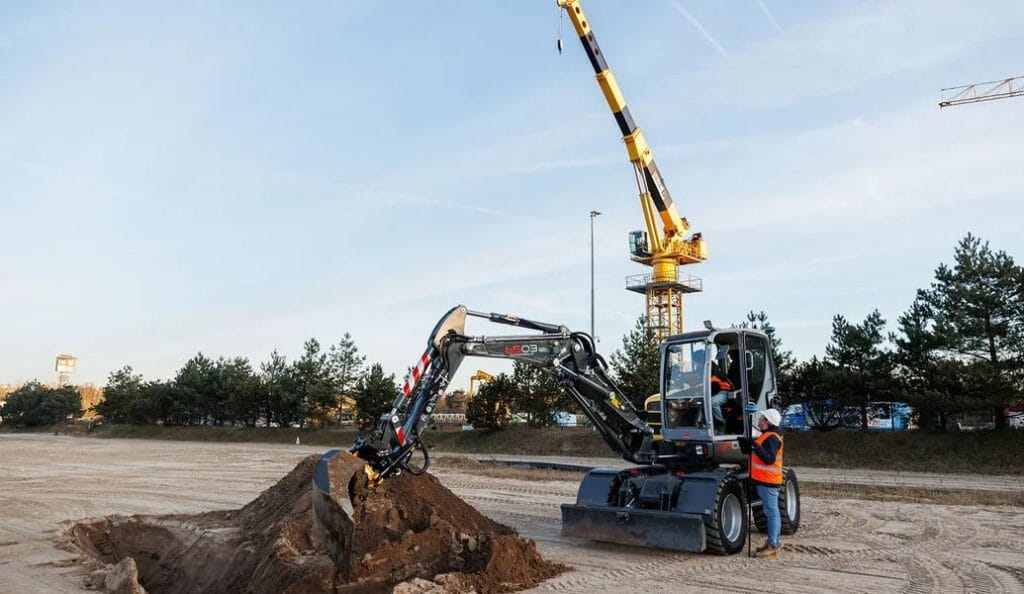 An excavator digging out a foundation with a spoil heap beside it