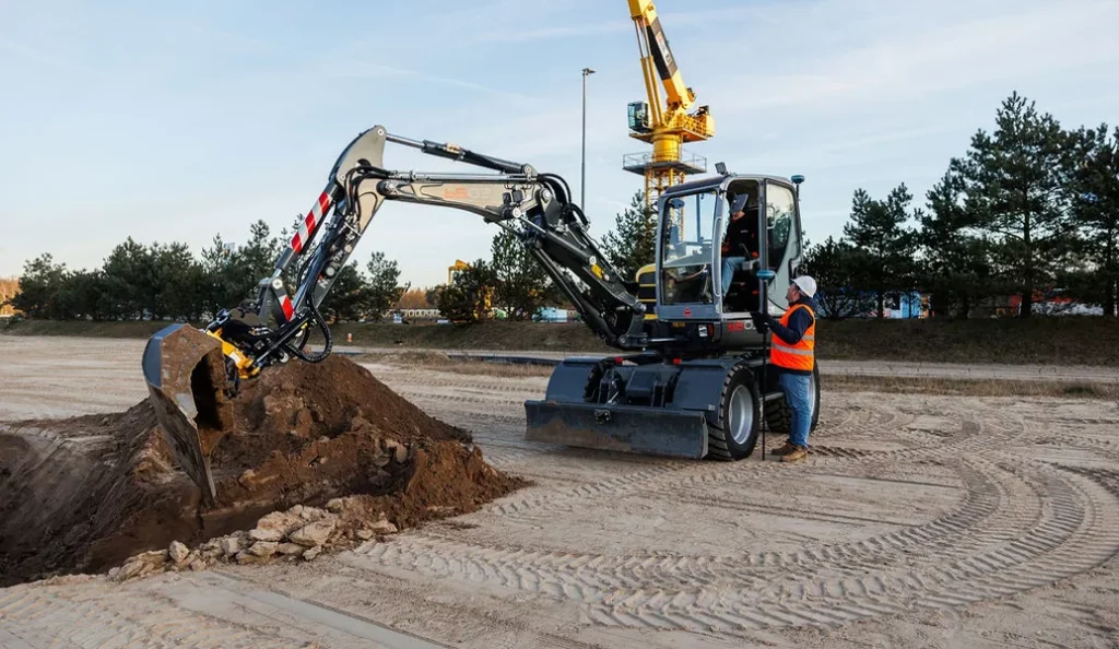 Ein Bagger mit UNI-Machine, der auf einer Baustelle Erde bewegt