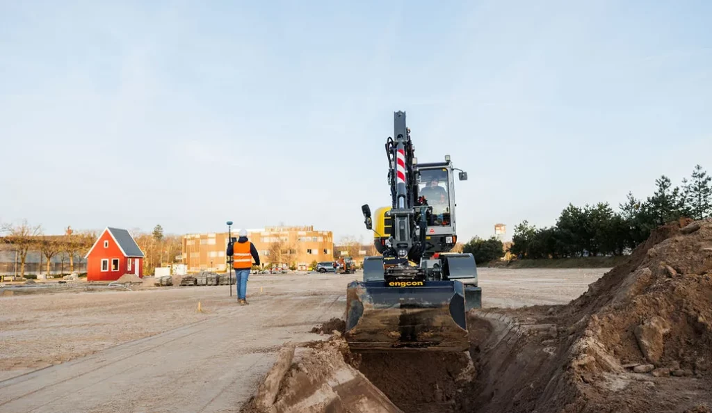 Ein Bagger, der einen offenen Graben für Kabel und Leitungen aushebt