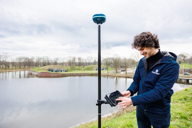 Colleague in a marXact hoodie checking the tablet on a UNI-GR2 pole by the water