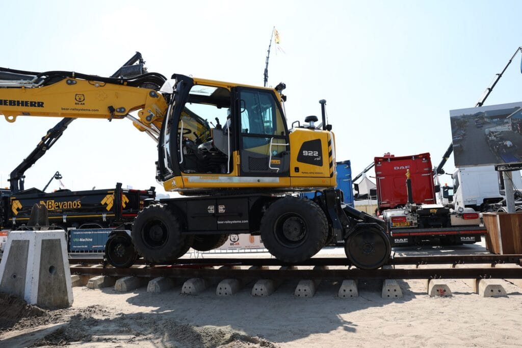 Yellow road-rail excavator with GNSS receivers on a track section, side view