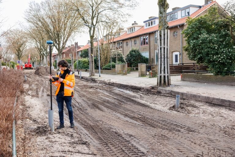 Surveyor with a UNI-GR2 and tablet along the kerb of an unpaved residential street