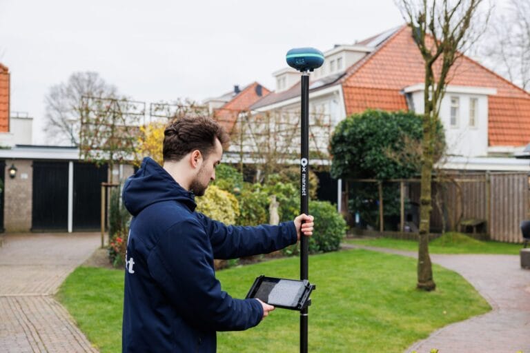 Man in a navy hoodie surveys a garden with a UNI-GR2 on a pole and a tablet