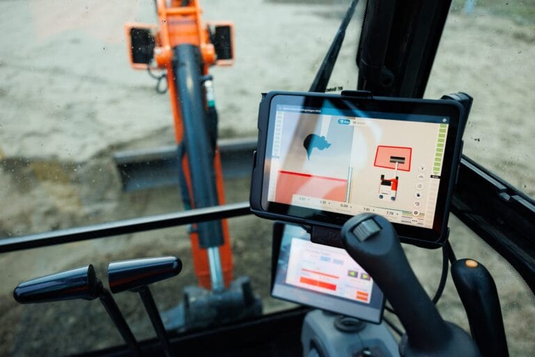 UNI-Machine screen showing bucket and design line in a mini excavator cab, boom visible through the glass