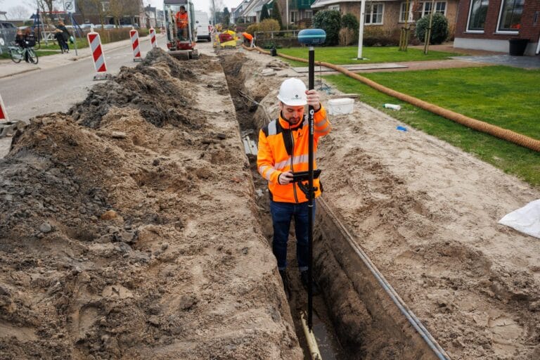 Worker in orange standing in a cable trench with the UNI-GR2 on a pole and a tablet